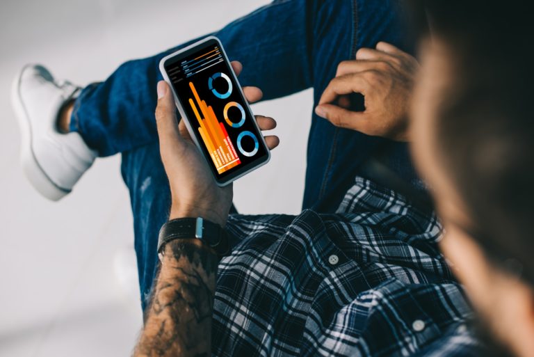 cropped view of man using smartphone with charts and graphs